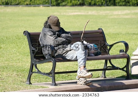 a homeless man sleeping on a park bench