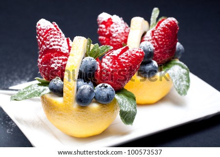 Fruit composition: strawberry and blueberry in a lemon basket with mint leaf
