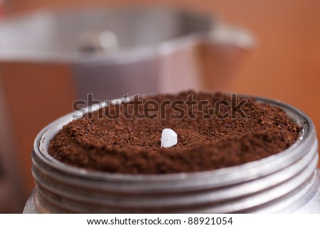 The image is an espresso coffee maker with a small grain of salt to ground coffee put together. The result is a coffee with a special flavor.