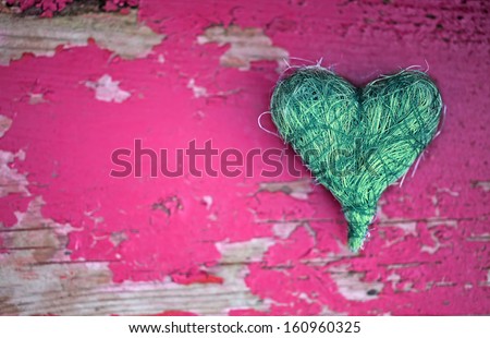 Green heart on pink wooden background