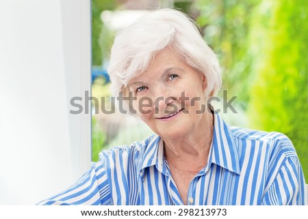 Beautiful senior woman sitting in her winter garden , in the background the garden