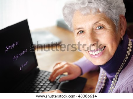 Senior woman portrait, typing on laptop and smiling great at camera. With text on laptop: