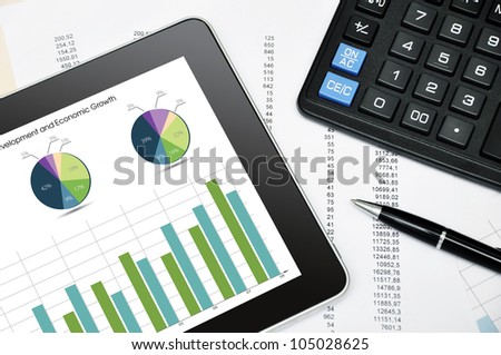 Modern business workplace with digital tablet, calculator, pen and printed data sheet