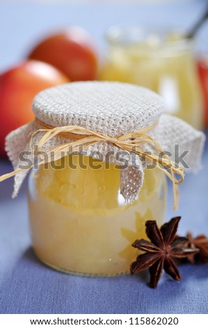 Apple jam in jar with cinnamon and fresh apples closeup