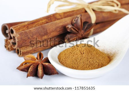 Cinnamon sticks, anise and cinnamon powder closeup on light background