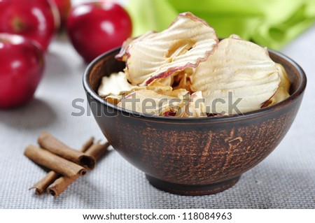 Dried apples chips in ceramic bowl with fresh red apples on table. Small shallow DOF.