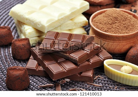 Milk and white Chocolate, cacao powder and chocolate candies over dark background