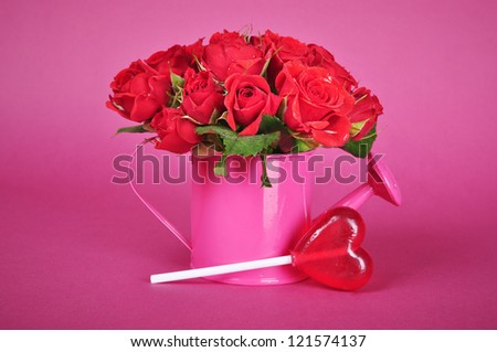 bouquet of red roses in a pink watering can on a pink background.