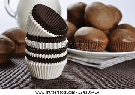 Brown and white cupcake cases with chocolate cupcakes on dark background