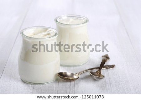 Greek Yogurt In A Glass Jars With Spoons On Wooden Background