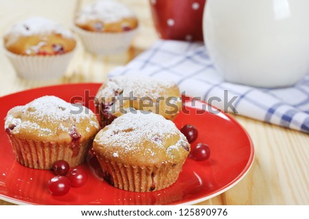Cranberry muffins on red plate with fresh berries and milk in a glass jug