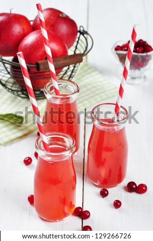 Cranberry juice in glass jars and fresh apples in vintage basket on a white  wooden background