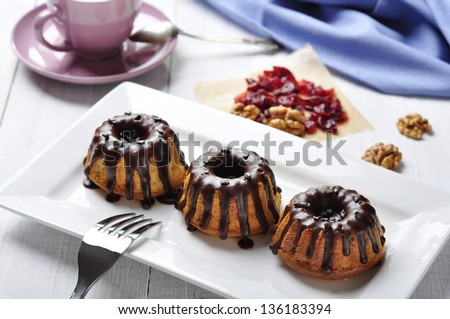Cake with melted chocolate icing on white dish on wooden background