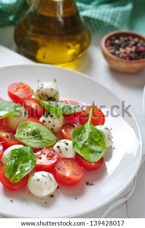 Caprese Salad on white plate with olive oil on wooden background