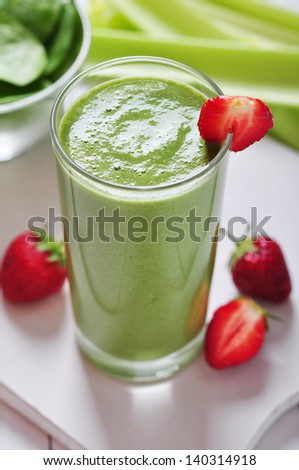 Green vegetable smoothie with celery and strawberry on wooden background