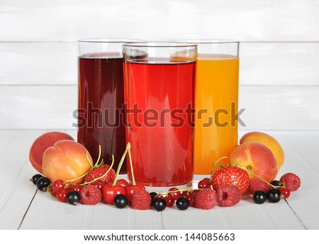Berry juice in glasses with fresh berries on wooden background