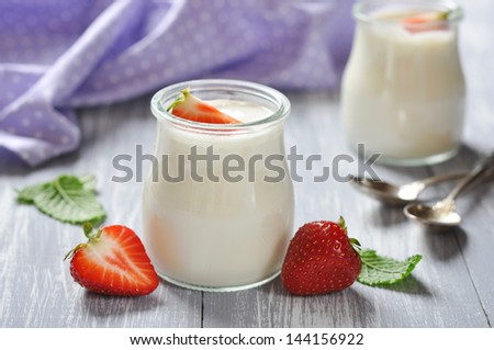 yogurt with ripe fresh strawberry in jars on wooden background