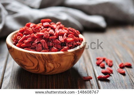 wooden bowl with goji berries on the table closeup