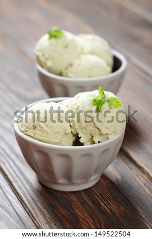 Vanilla ice cream with mint in ceramic bowl on wooden background