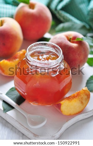 peach  jam in glass jar on white wooden background