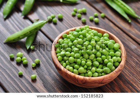 Green peas in wooden bowl on wooden background
