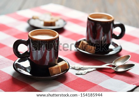 Two cups of espresso in brown cups on checkered napkin