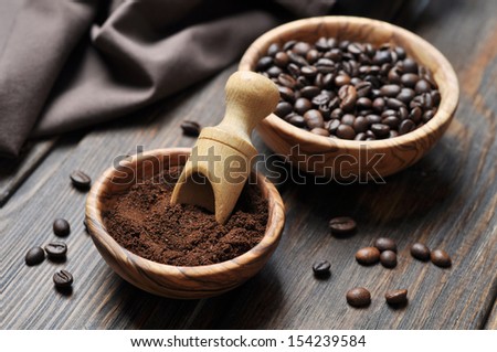ground coffee and coffee beans in bowls on wooden background