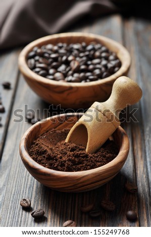 ground coffee and coffee beans in bowls on wooden background