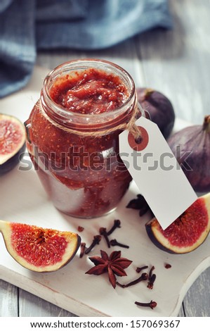 Fig jam in a glass jar with  fresh figs on wooden background