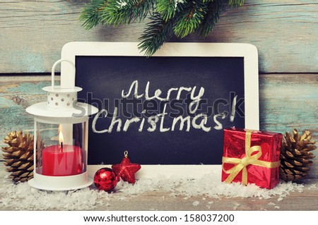 Christmas  decoration with candle in lantern and framed blackboard on wooden background