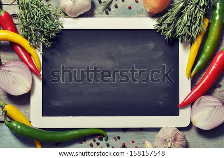 Slate board with fresh vegetables, spice and herbs on wooden background. Top view.
