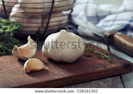 Fresh garlic on cutting board on vintage wooden background