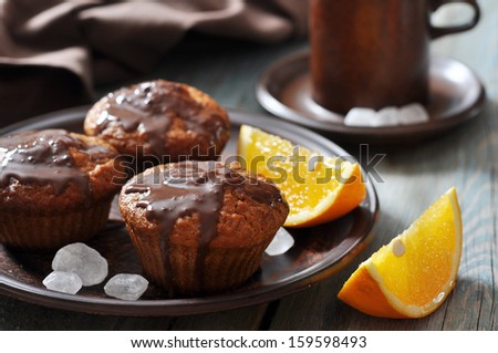 Carrot muffins with melted chocolate and fresh oranges fruit on wooden background