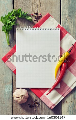 Blank recipe book with kitchen towel on wooden background