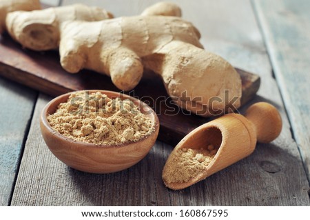 Fresh ginger root and ground ginger spice on wooden background
