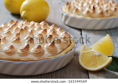 Lemon Meringue Pie with fresh lemons on wooden background