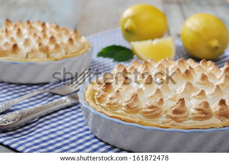 Lemon Meringue Pie with fresh lemons on checkered background