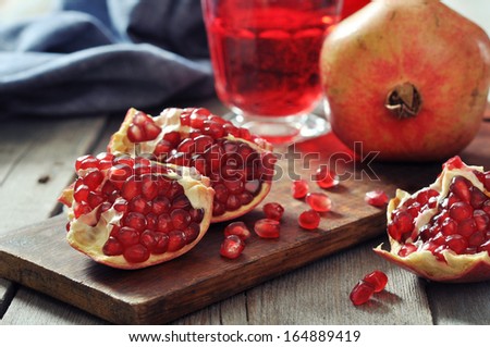 Ripe pomegranate fruit and glass of juice on wooden background
