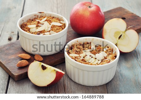 Apple crumble in ceramic molds with fresh apples on wooden background