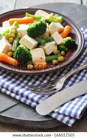 Tofu with  boiled vegetables on plate closeup