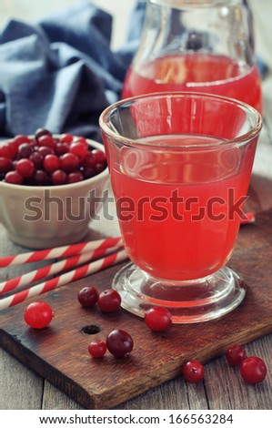 Cranberry juice in glass with fresh berry on wooden background