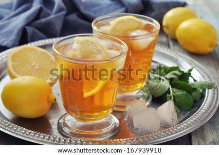 Ice tea in glass with lemon and mint on metal tray