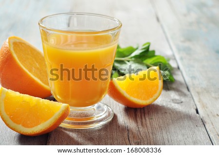 Orange juice in glass with mint,  fresh fruits on wooden background