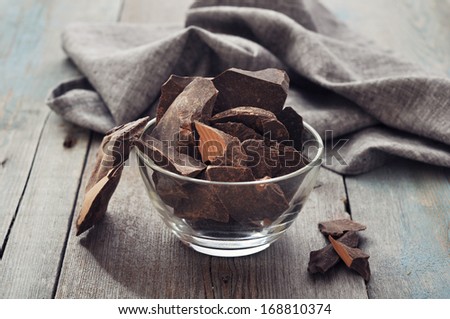 Chocolate pieces in glass bowl  on wooden background
