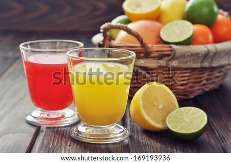 Citrus juice and fruits in wicker basket on wooden background