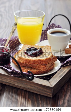 Breakfast with toast, fruit jam, orange juice and coffee on tray