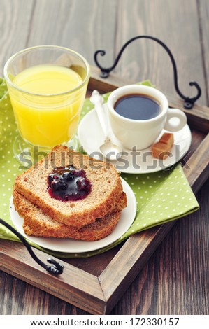 Breakfast with toast, fruit jam, juice and coffee on tray