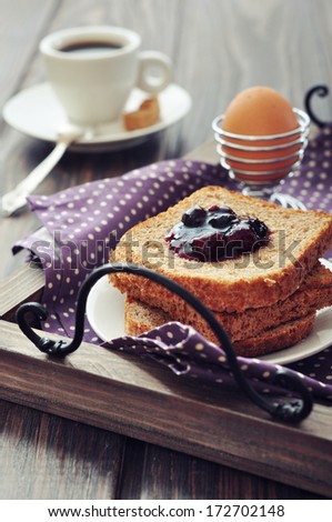 Breakfast with toast, fruit jam, boiled egg and coffee on tray