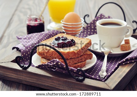 Breakfast with toast, fruit jam, orange juice and coffee on tray