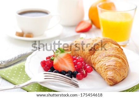 Fresh croissant with berries, coffee and orange juice closeup